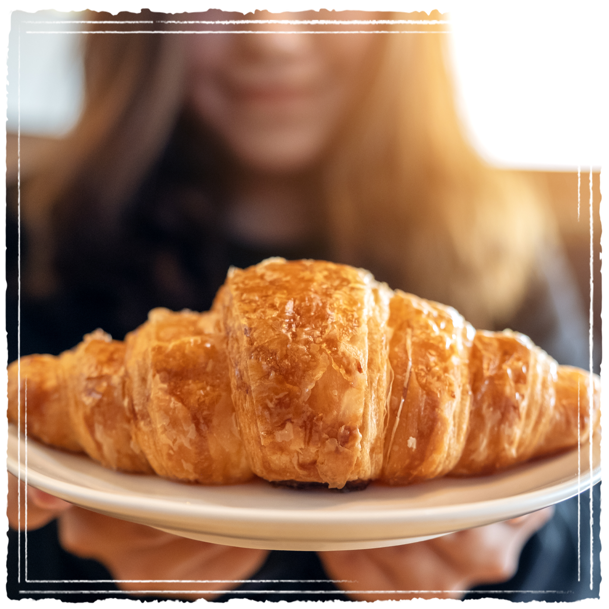 Close up of fresh croissant on plate served by woman