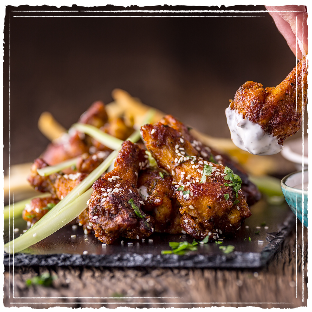 Close up of specialty chicken wings garnished and plated with dipping sauce