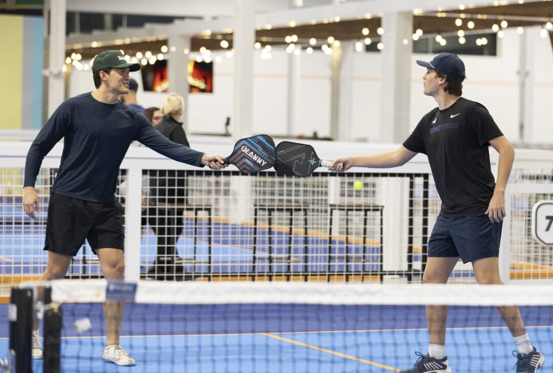 Two young men tapping their pickleball paddles in sportsmanship after a game
