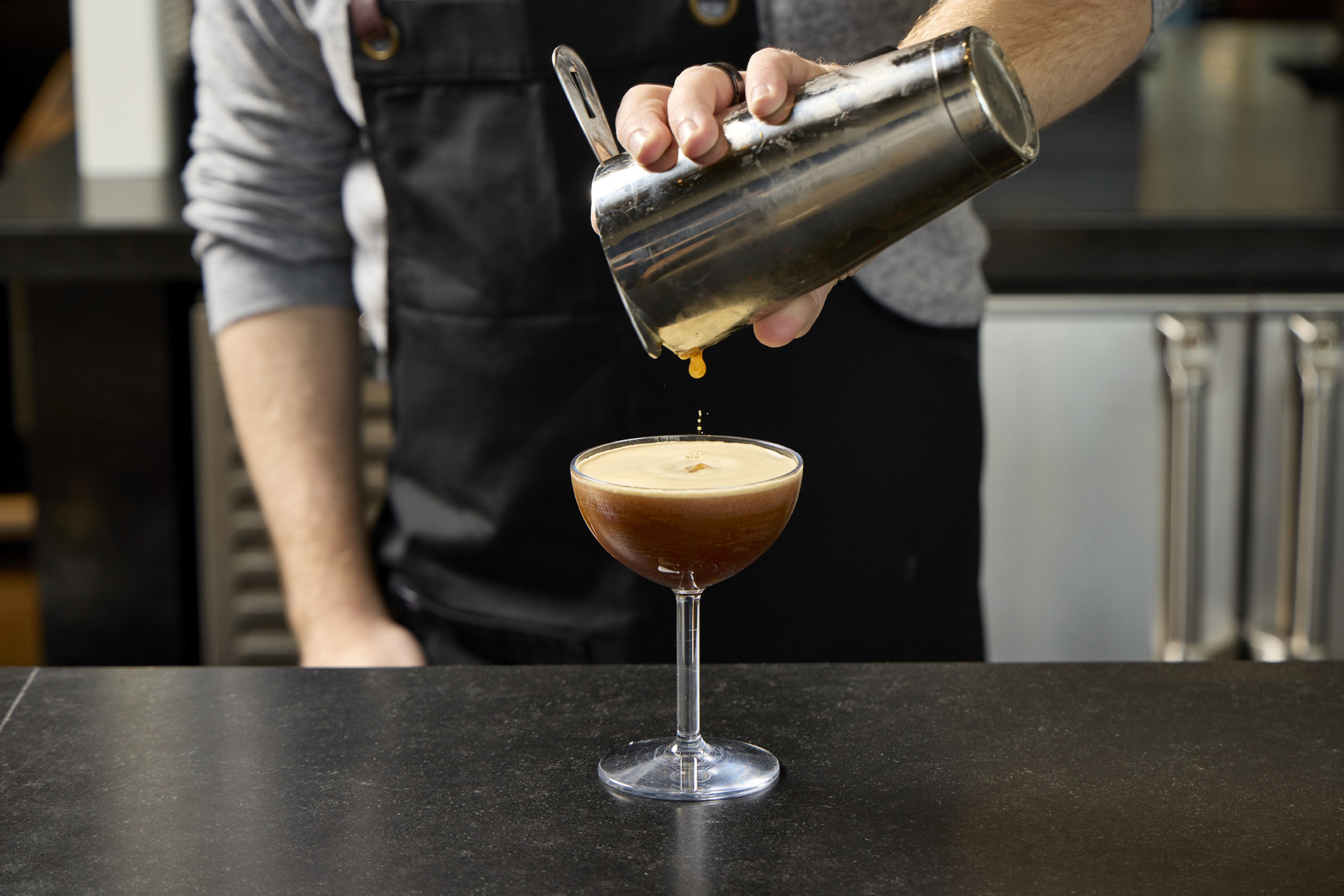 bartender pouring espresso martini in glass