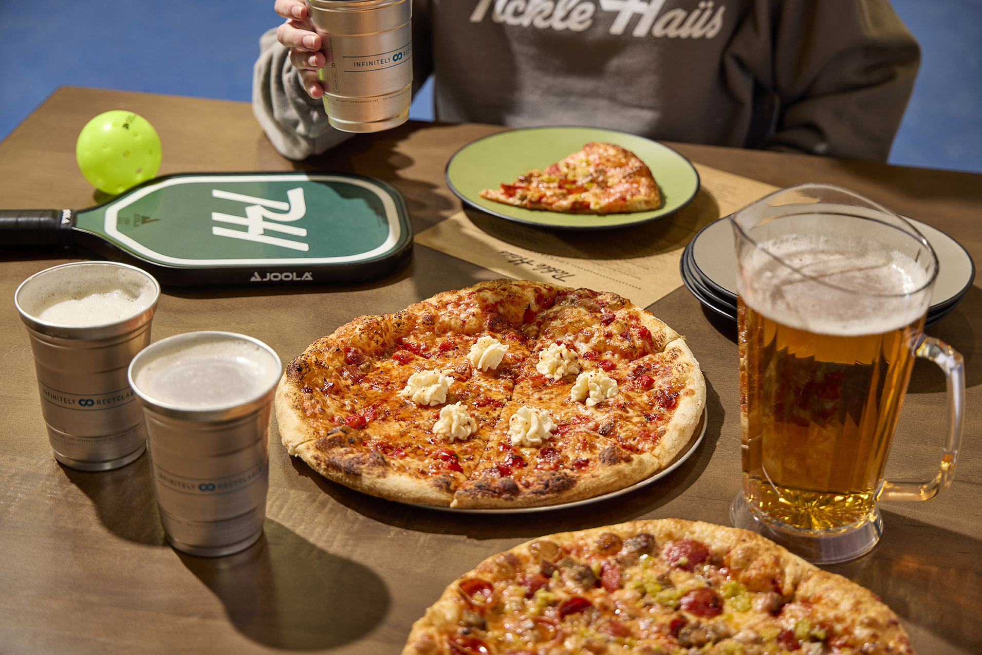 table with pizza, beer pitcher and pickleball racquet and ball