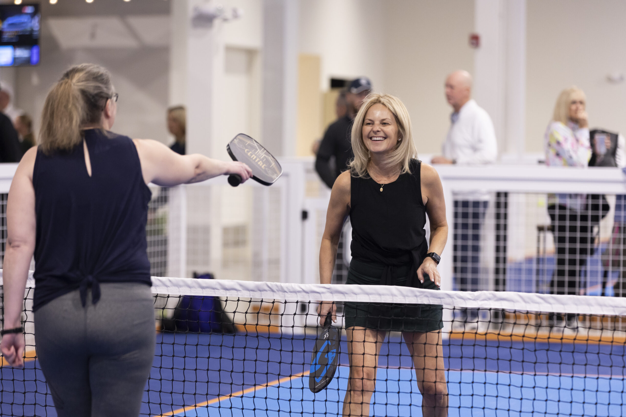 middle aged woman playing pickleball and laughing