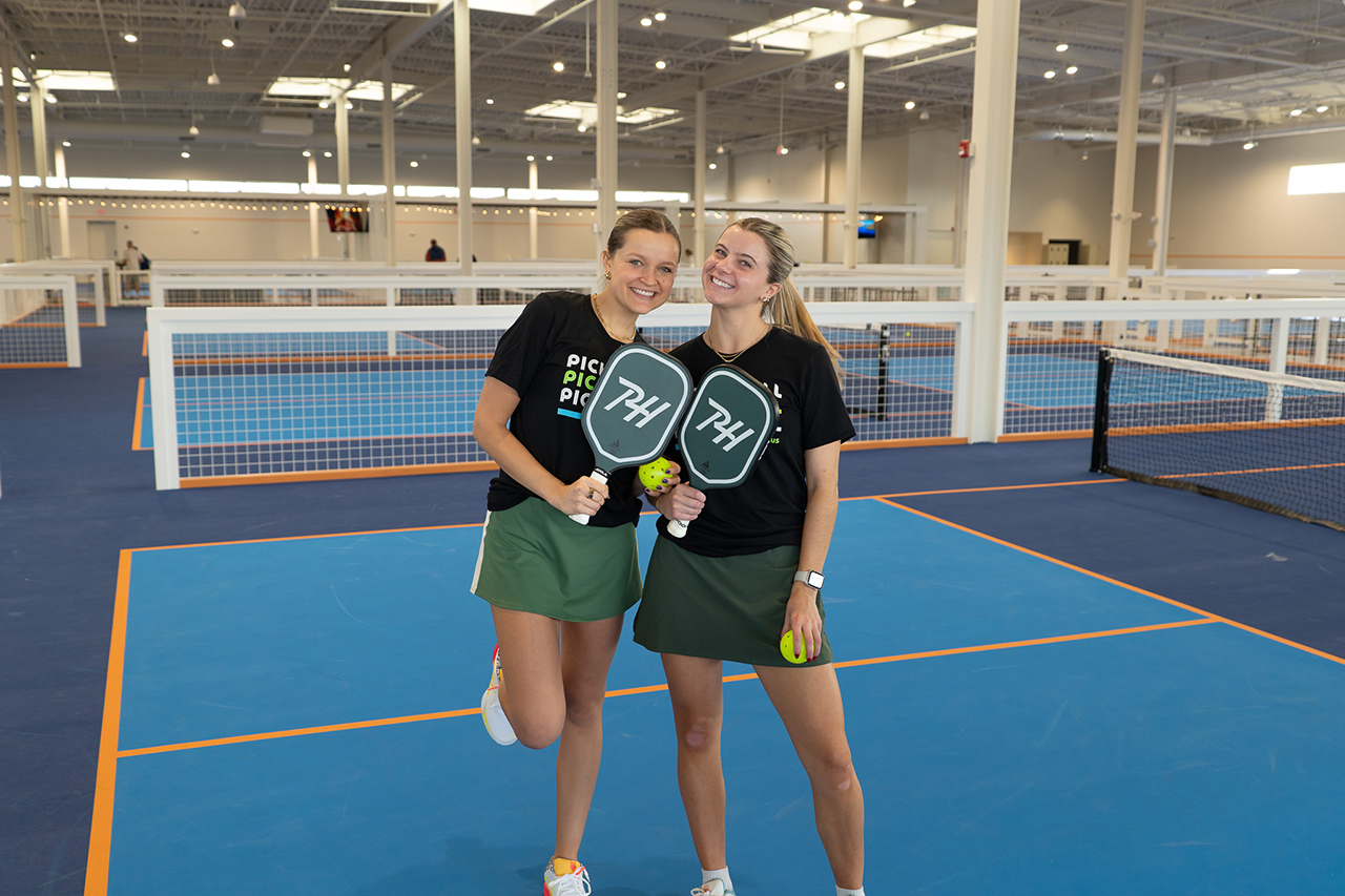 2 young women posing on the pickleball court