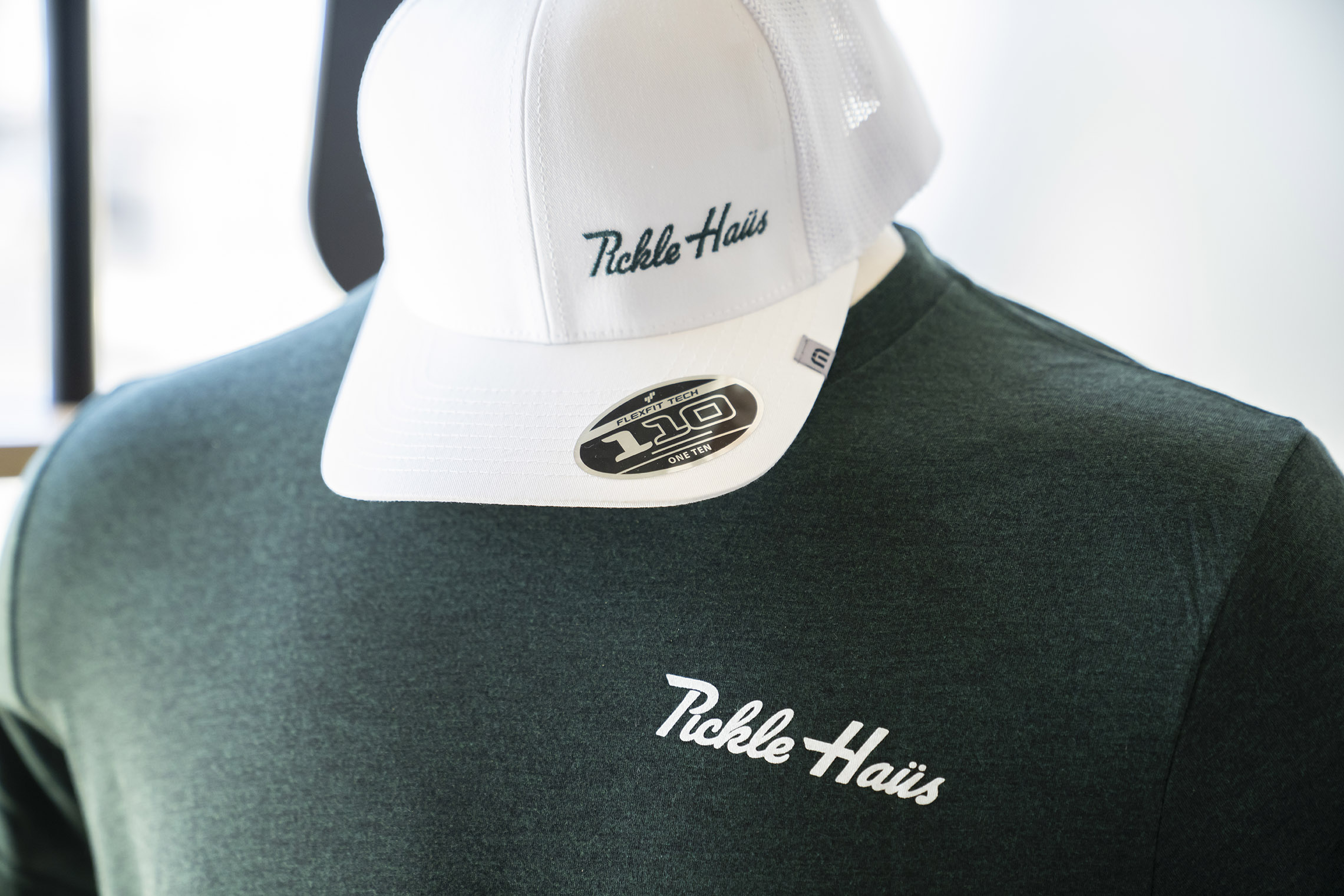 white pickle haus cap with green t-shirt with logo on the chest