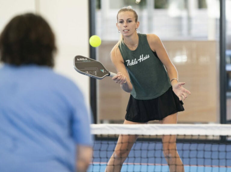 Woman holding a pickleball paddle and preparing for a serve on the court