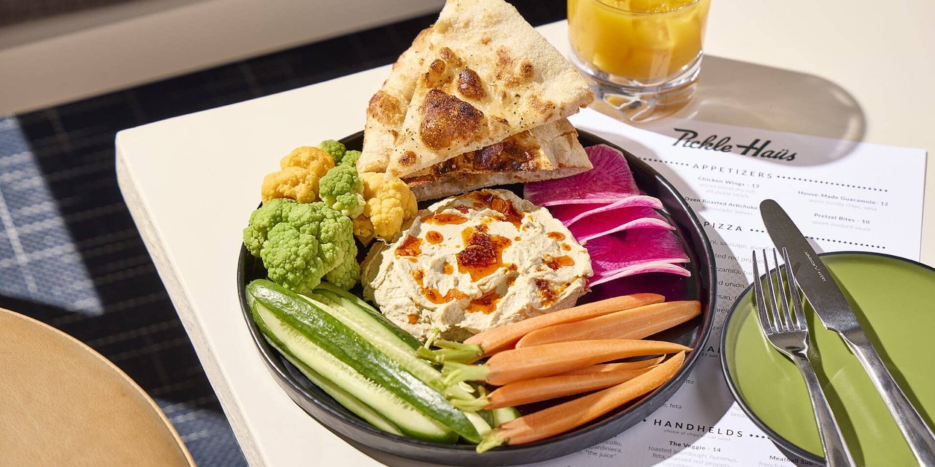Hummus platter with fresh vegetables and pita bread at Pickle Haus